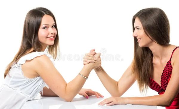 two women arm wrestle in dresses